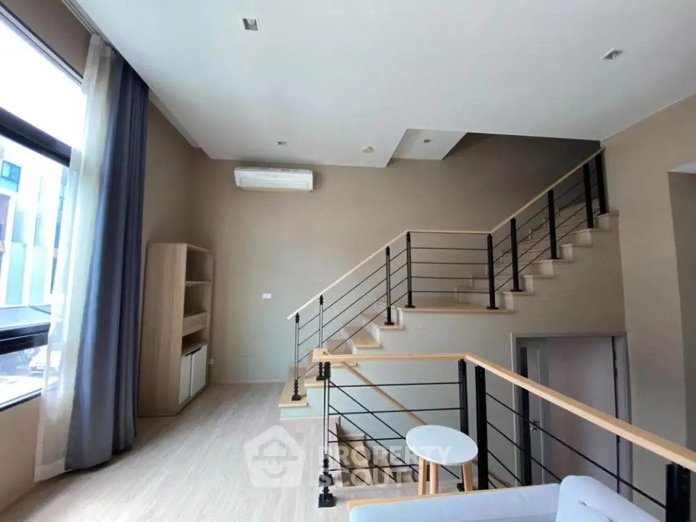 Spacious modern living room with high ceiling and stylish staircase