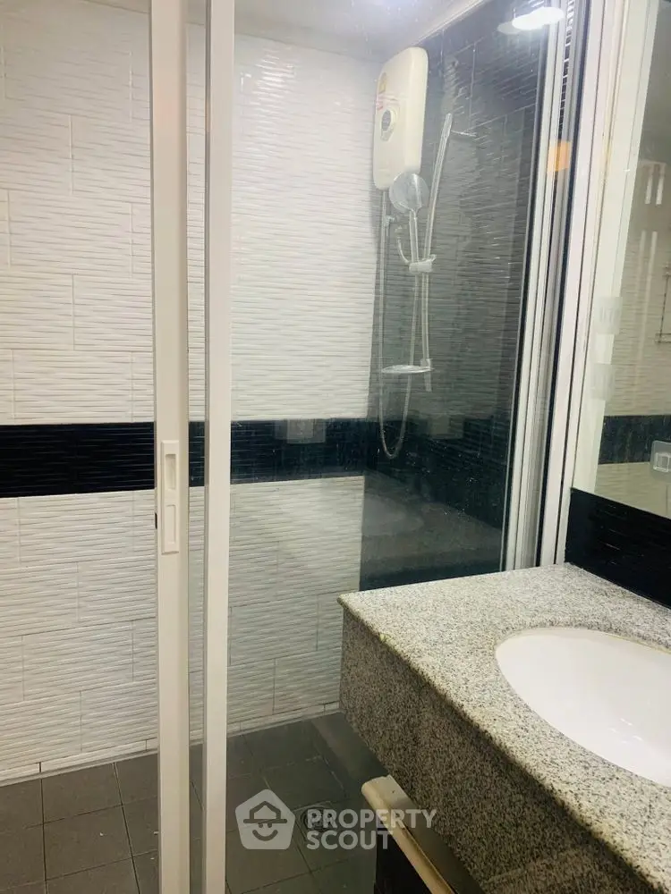 Modern bathroom with sleek shower and granite countertop in contemporary apartment.