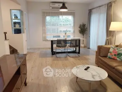 Spacious living room with modern decor and natural light, featuring a cozy seating area and dining space.