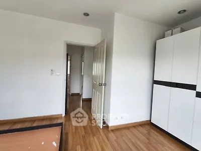 Spacious bedroom with wooden flooring and modern wardrobe in a minimalist design.