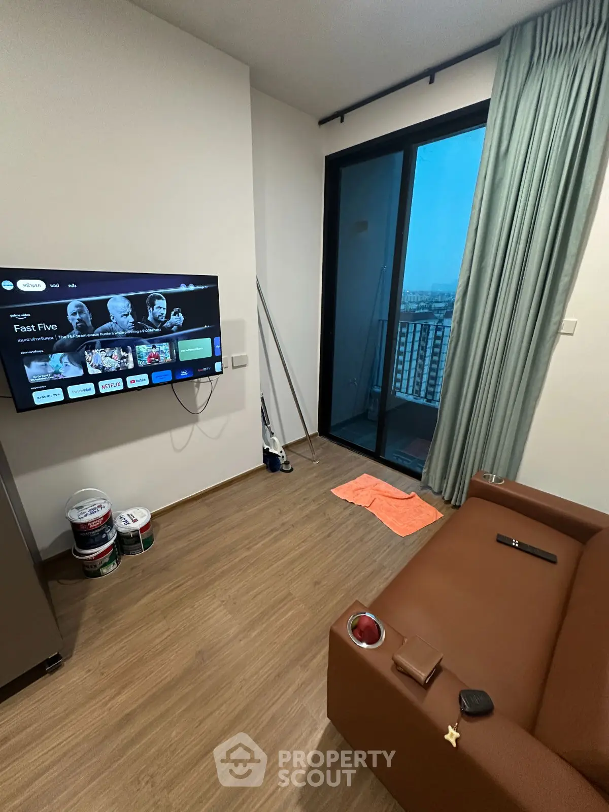 Modern living room with wall-mounted TV and balcony view, featuring sleek design and cozy ambiance.
