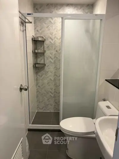 Modern bathroom with glass shower door and sleek fixtures in contemporary apartment.