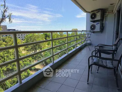Spacious balcony with scenic view and seating area in modern apartment.