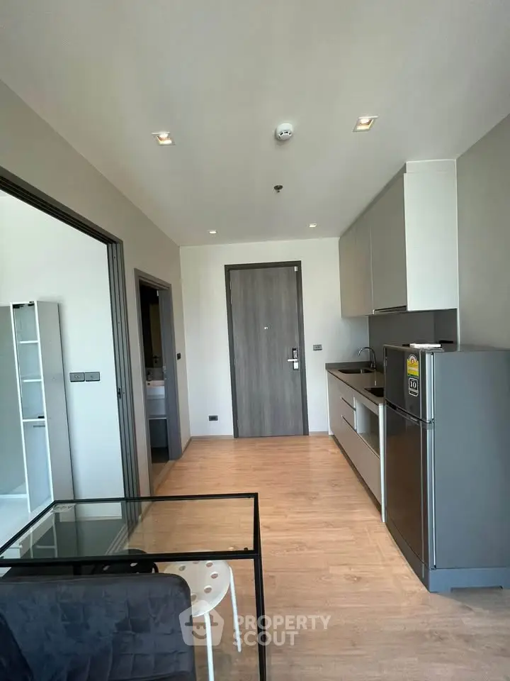 Modern apartment interior with open kitchen and dining area, featuring sleek appliances and stylish decor.