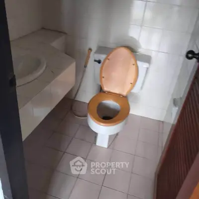 Compact bathroom with tiled walls and floor, featuring a toilet and sink.