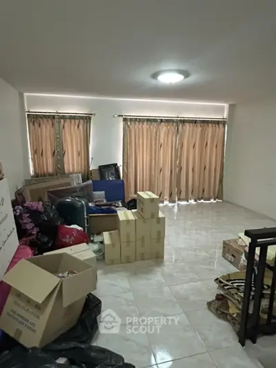 Spacious room with tiled floor and large windows, ideal for storage or customization.