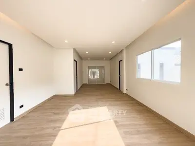 Spacious modern living room with wooden flooring and ample natural light.