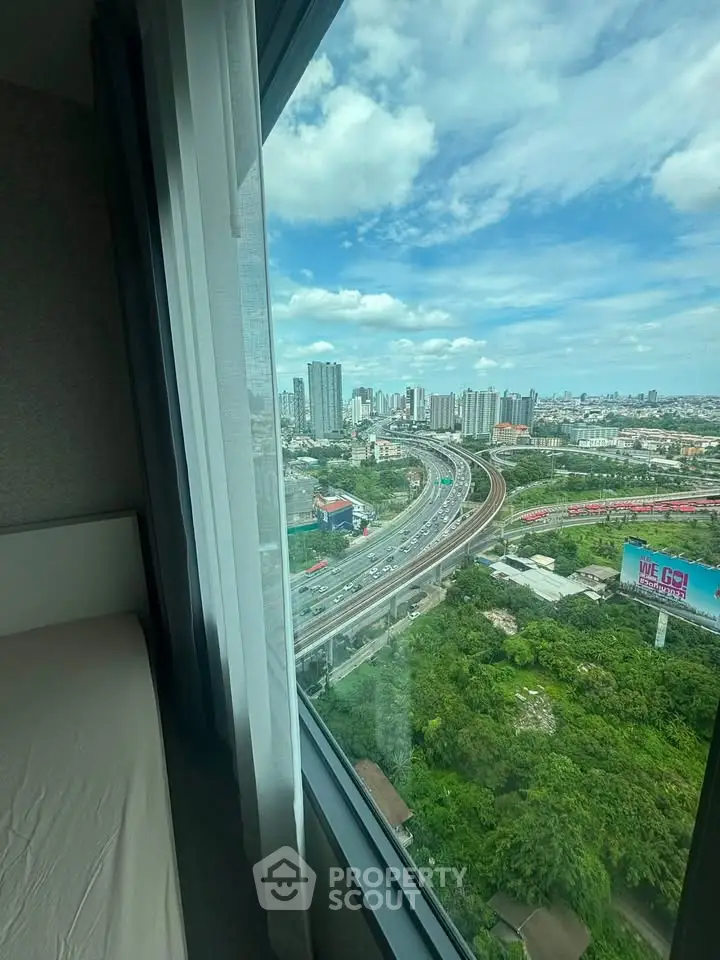Stunning high-rise city view from a modern apartment window, showcasing urban skyline and lush greenery.