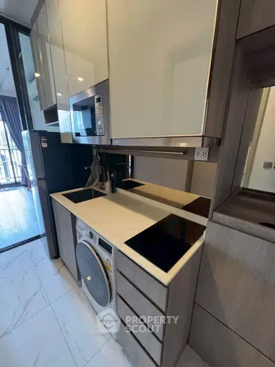 Modern compact kitchen with sleek appliances and washer in stylish apartment