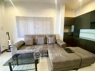 Modern living room with stylish gray sectional sofa and sleek glass coffee table.