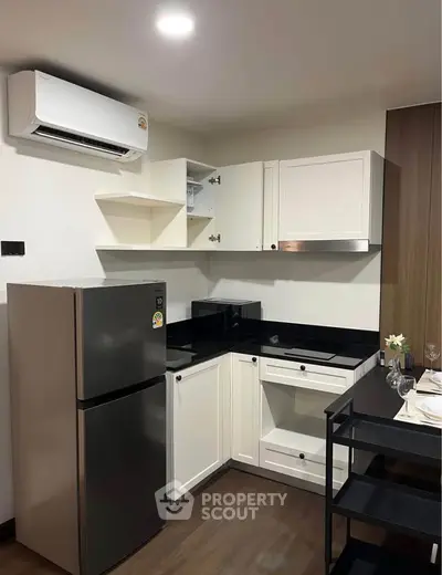 Modern kitchen with sleek black countertops and stainless steel appliances in a stylish apartment.