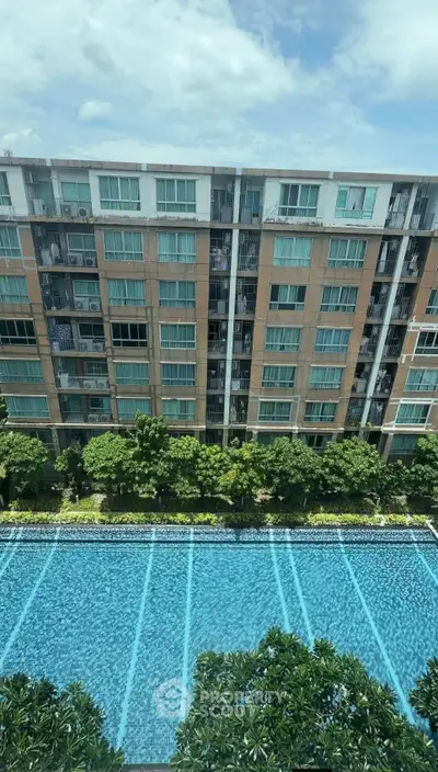 Modern apartment building with a stunning pool view and lush greenery.