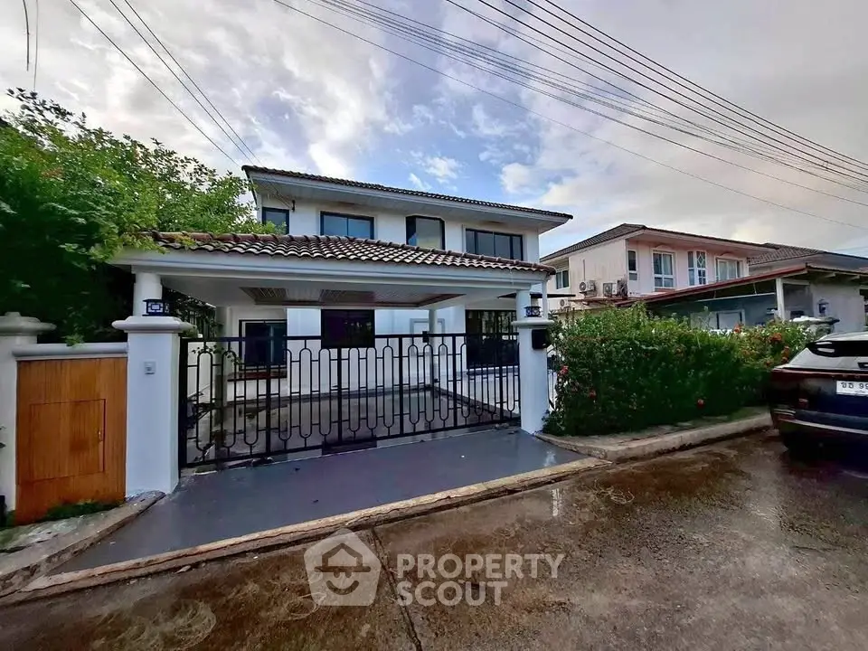 Charming two-story house with gated entrance and lush greenery in a serene neighborhood.