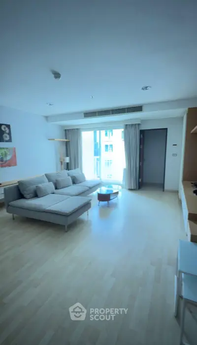 Spacious modern living room with large windows and stylish furniture in a bright apartment.