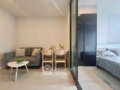 Modern studio apartment with cozy living area and stylish bedroom separated by glass partition.