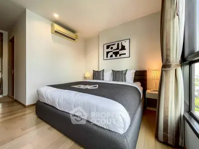 Modern bedroom with stylish decor and large window offering natural light