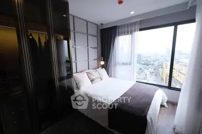Modern bedroom with large window offering city view, elegant decor, and ample natural light.