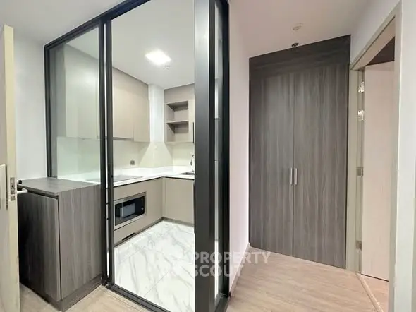 Modern kitchen with sleek cabinetry and glass partition in a stylish apartment.