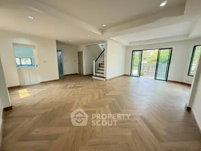 Spacious open-plan living room with elegant wood flooring and large windows
