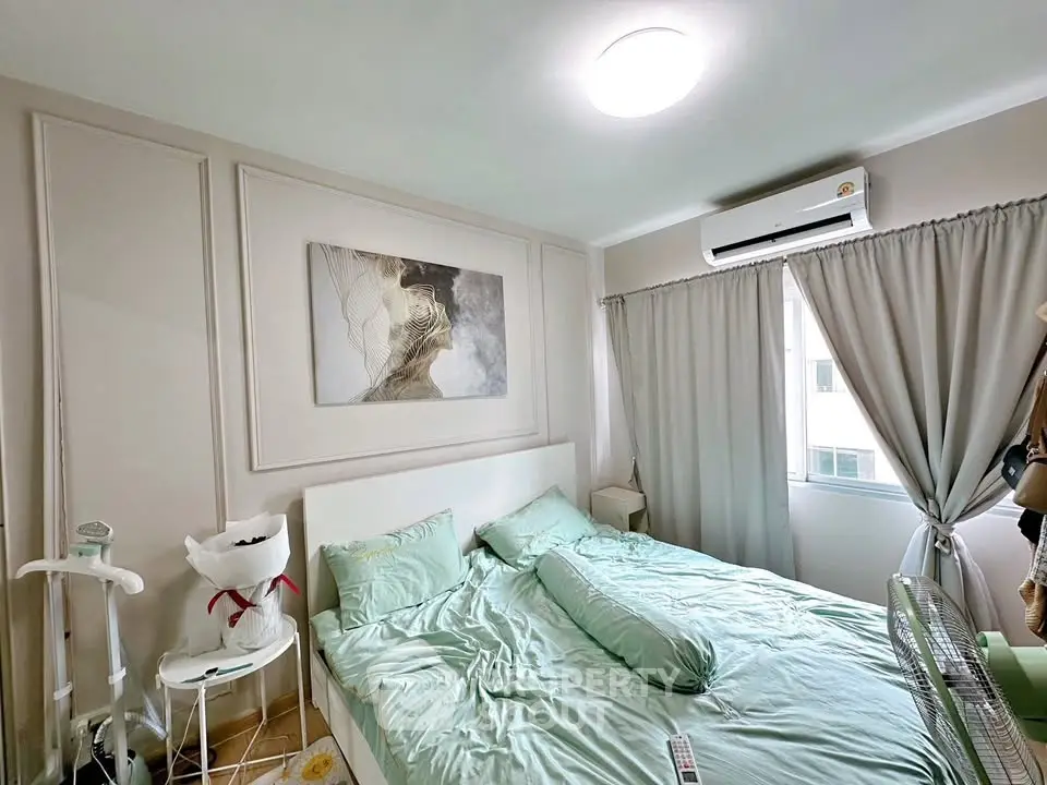 Cozy bedroom with modern decor and natural light, featuring air conditioning and stylish wall art.