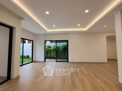 Spacious modern living room with wooden flooring and garden view, perfect for family gatherings.