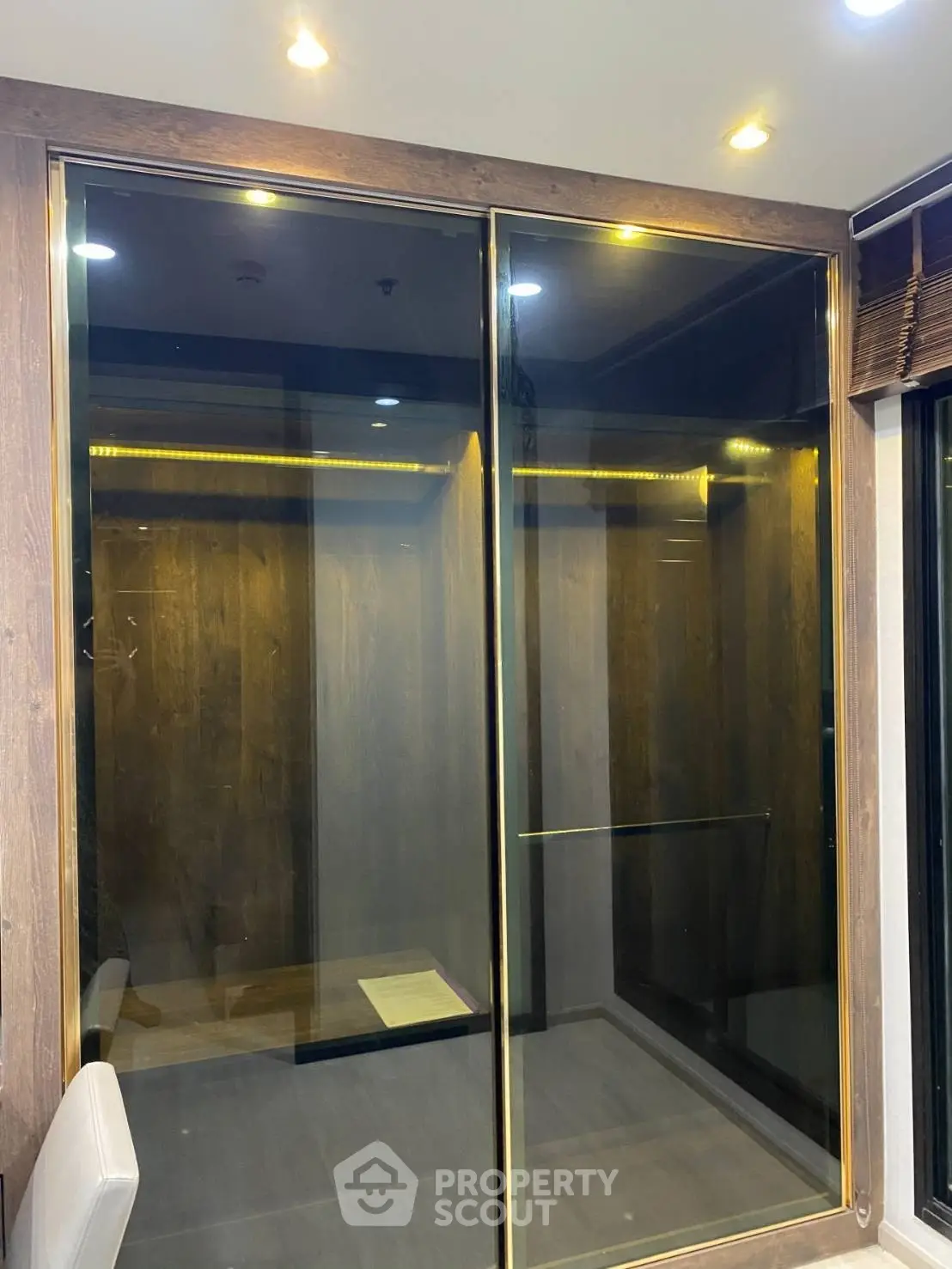 Luxurious modern elevator with sleek glass doors and ambient lighting in a high-end building.