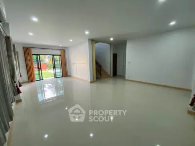 Spacious living room with large windows and garden view, perfect for family gatherings.