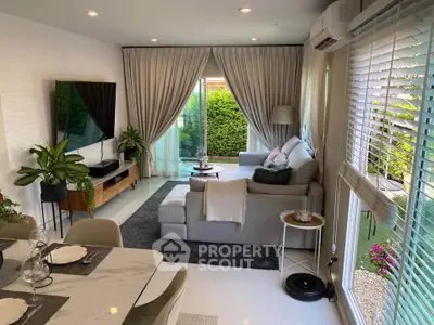 Modern living room with large windows, cozy sectional sofa, and lush garden view, perfect for relaxation.