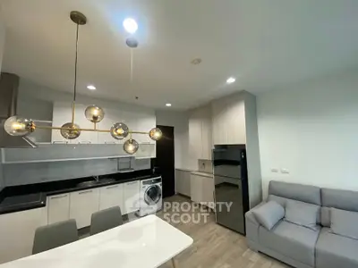 Modern open-layout kitchen and living room with stylish lighting and appliances.