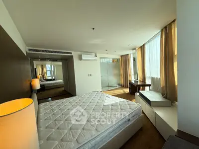 Spacious bedroom with large windows and modern furnishings in a luxury apartment.