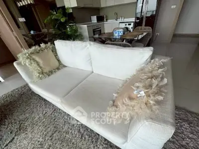 Modern open-layout living room with cozy white sofa and stylish kitchen area.