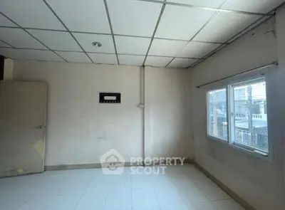 Spacious empty room with large window and tiled floor, ideal for customization.