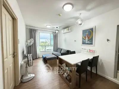Modern living room with stylish decor, featuring a cozy sofa, dining table, and large window with scenic view.