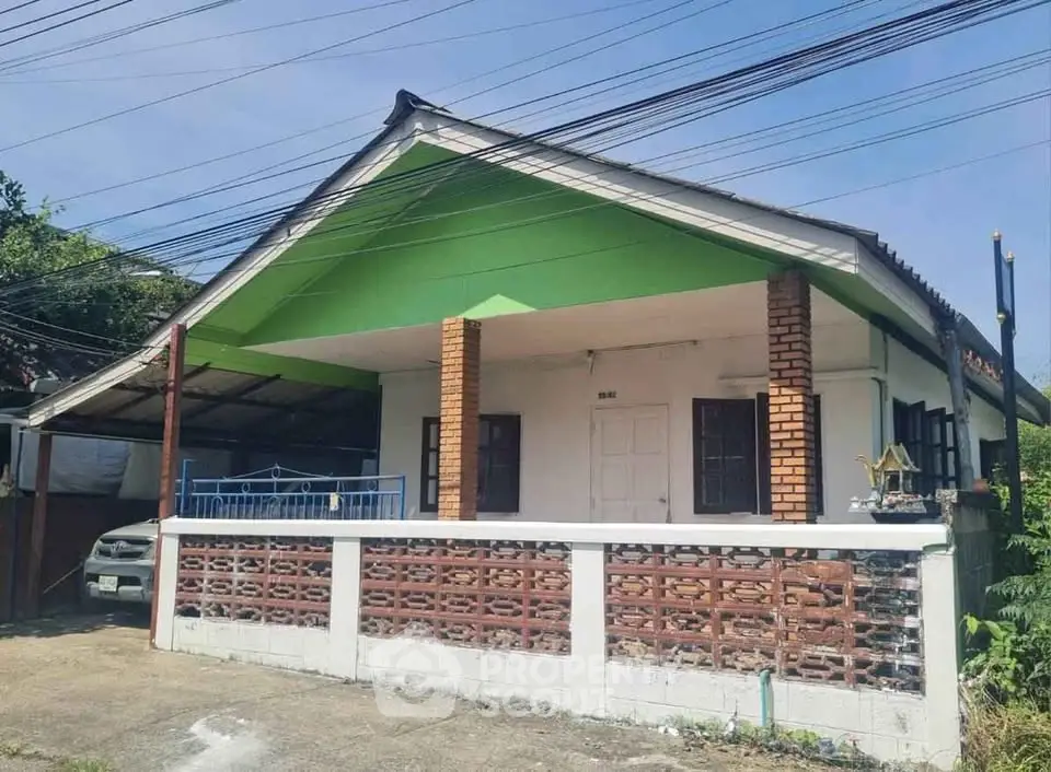 Charming single-story house with green accents and spacious front porch.
