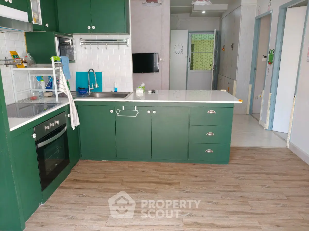 Charming kitchen with green cabinets and modern appliances, featuring a sleek open layout and stylish wood flooring.