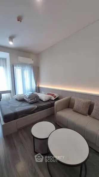 Modern studio apartment with cozy bed and stylish sofa, featuring elegant lighting and chic decor.
