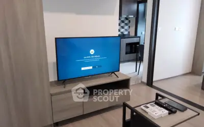 Modern living room with sleek TV setup and view into stylish kitchen area.