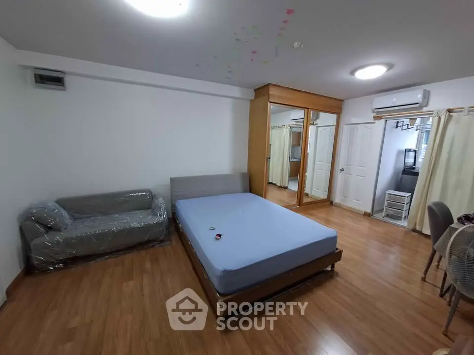 Spacious bedroom with wooden flooring, mirrored wardrobe, and modern furnishings.
