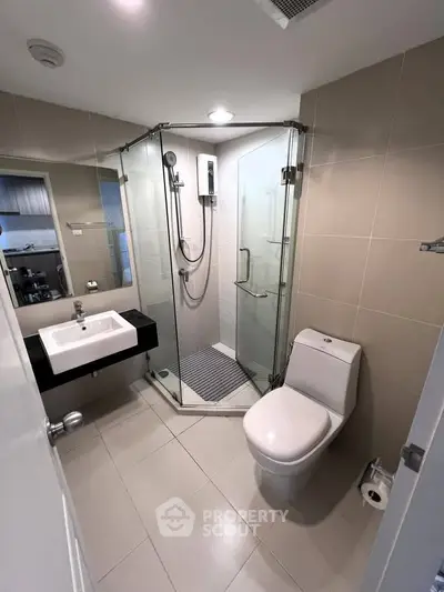Modern bathroom with glass shower enclosure and sleek fixtures in a contemporary apartment.