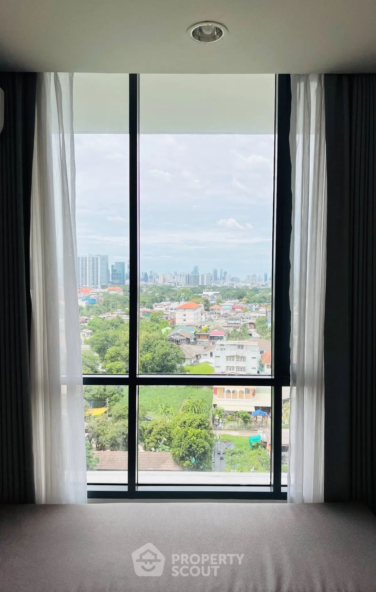Stunning cityscape view from a modern apartment window, showcasing urban skyline and lush greenery.