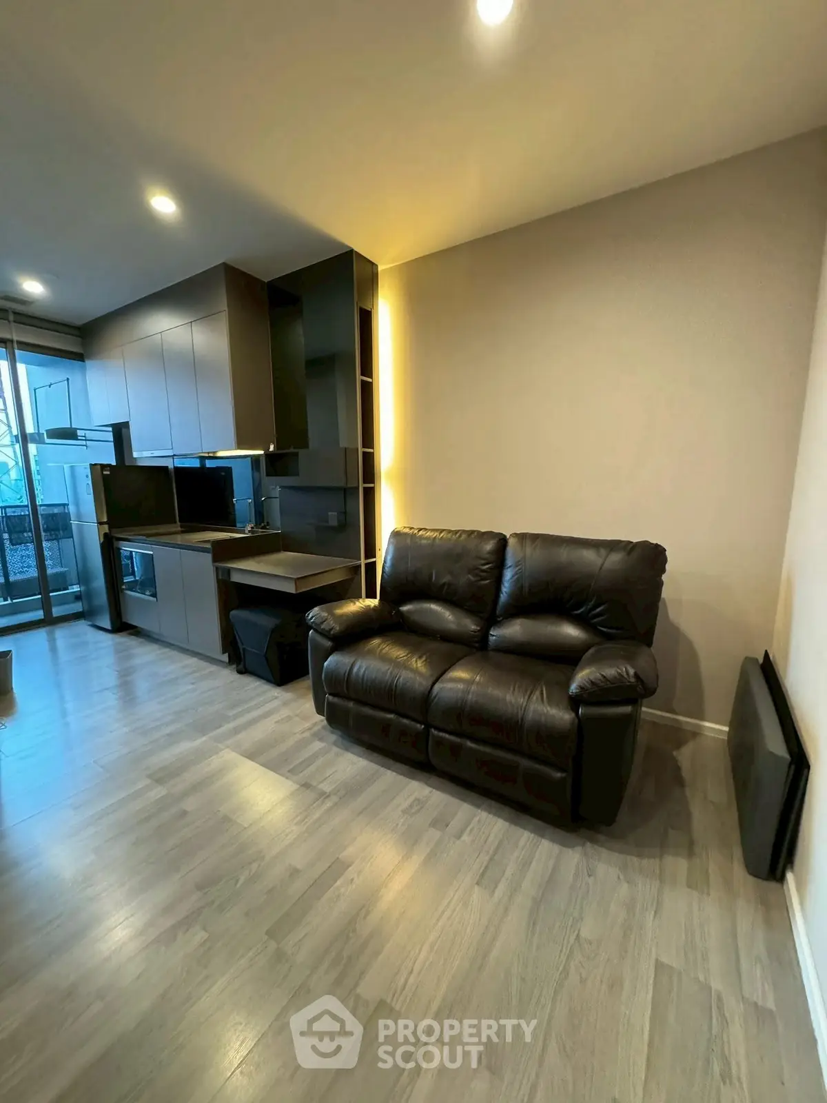 Modern living room with sleek kitchen and leather sofa in open layout apartment