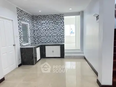 Spacious kitchen with modern mosaic backsplash, sleek marble countertops, and ample natural light, perfect for culinary enthusiasts.