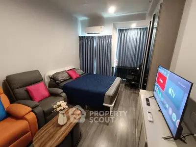 Modern studio apartment with cozy living area and smart TV, featuring stylish decor and ample natural light.