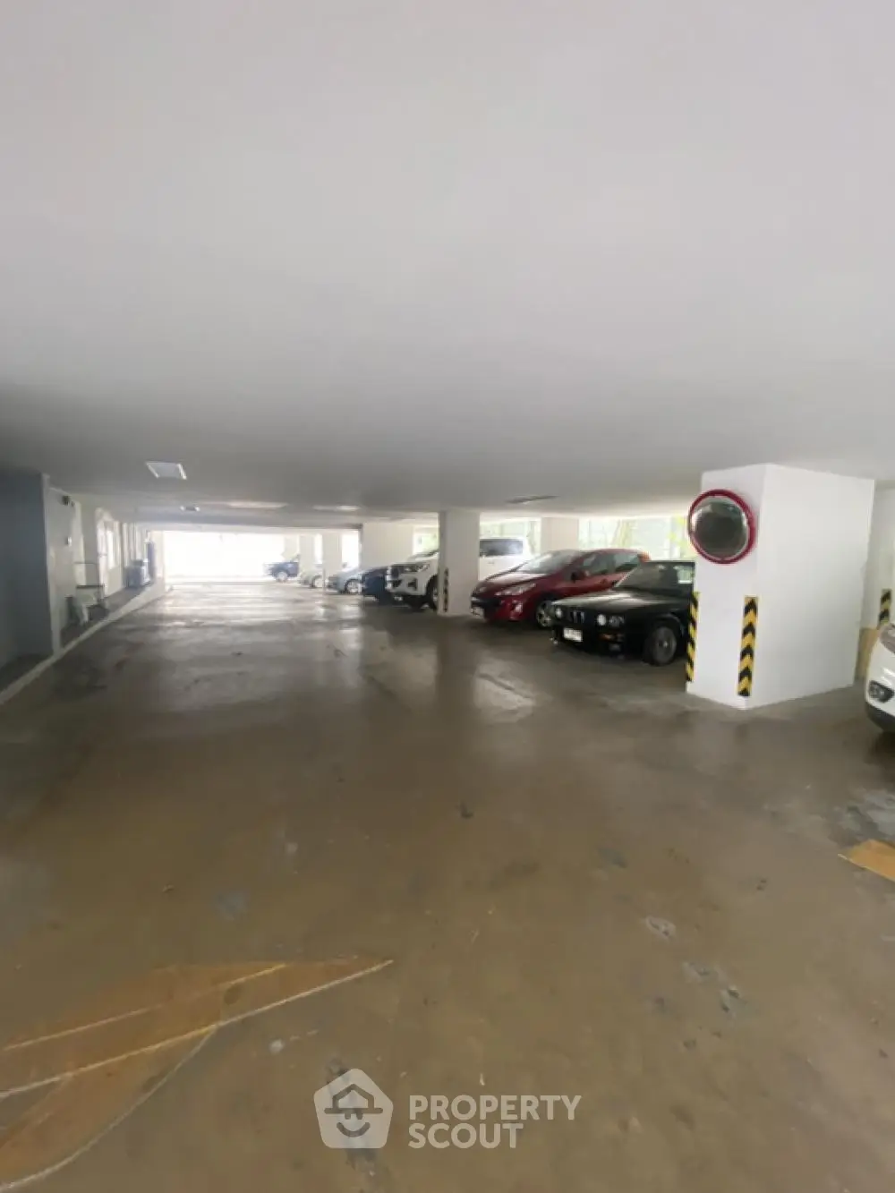 Spacious indoor parking area with multiple parked cars in a residential building.