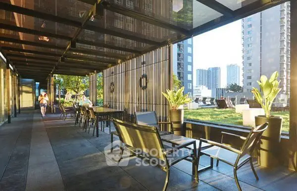 Modern outdoor seating area with city view and greenery in urban residential complex.