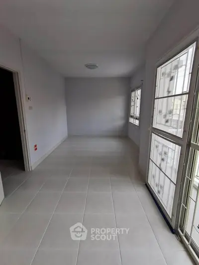 Spacious empty room with large windows and tiled flooring, perfect for customization.
