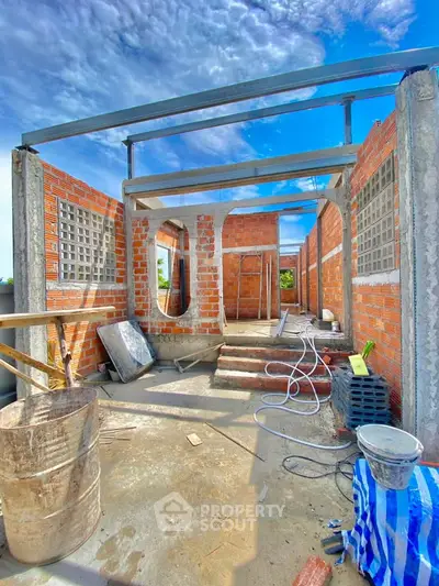 Under-construction property showcasing brick walls and open framework under a clear blue sky.