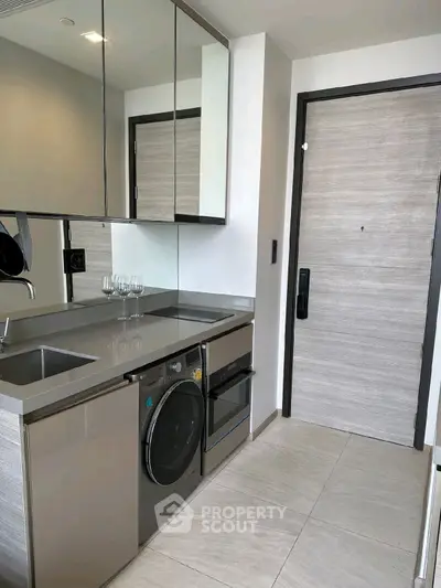 Modern compact kitchen with sleek appliances and mirrored cabinets