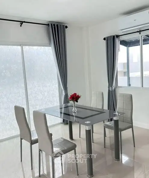 Modern dining area with glass table and elegant chairs in a bright, airy room.