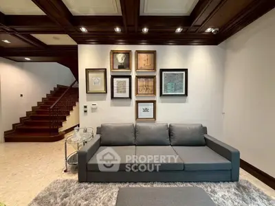Elegant living room with stylish sofa and art gallery wall, featuring wooden ceiling and staircase.